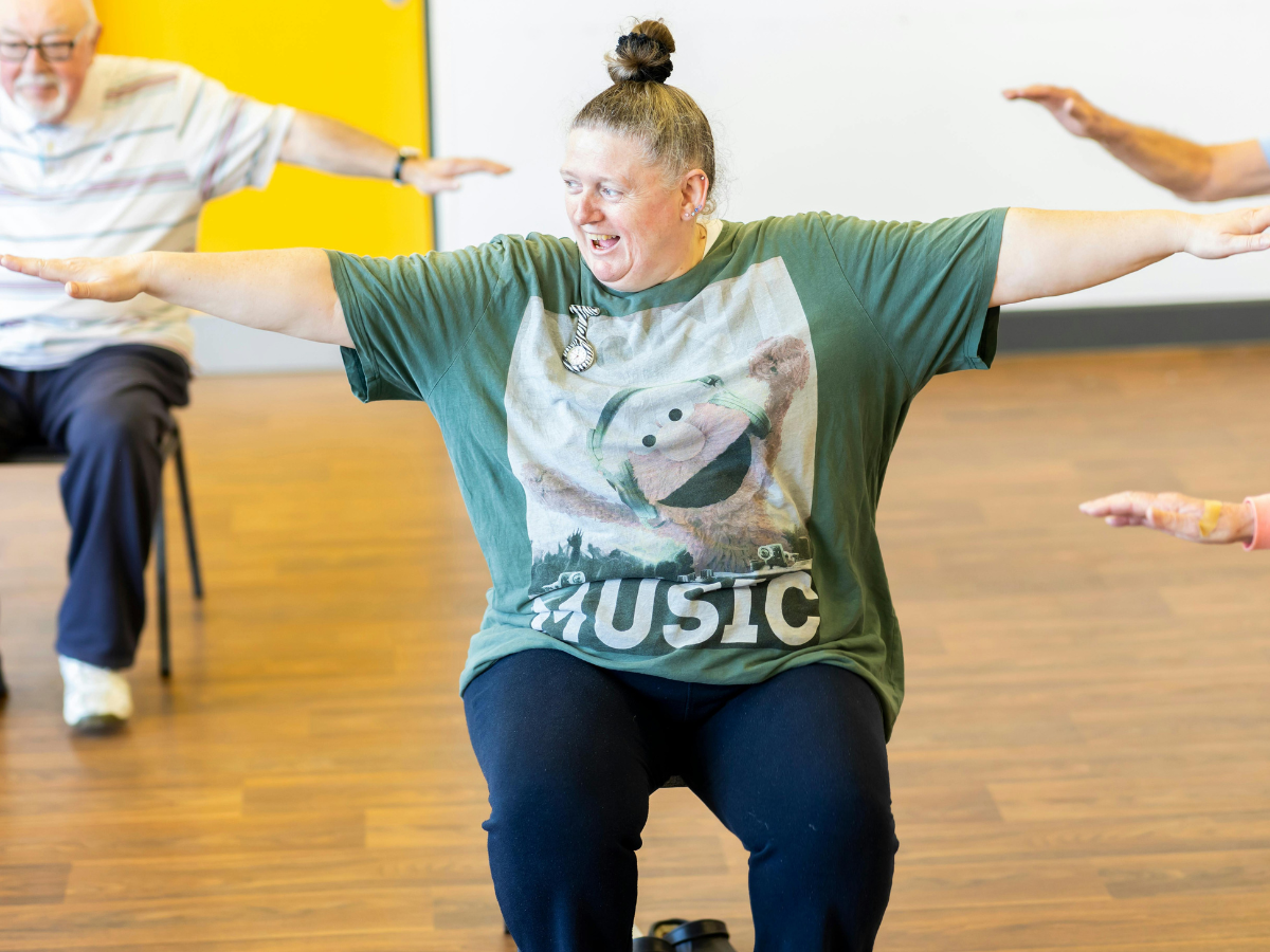 An lady taking part in seated exercise with outstretched arms